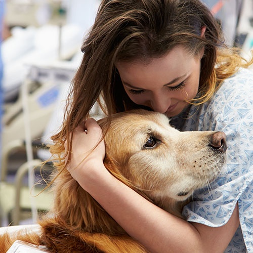 A woman in a hospital hugs a dog